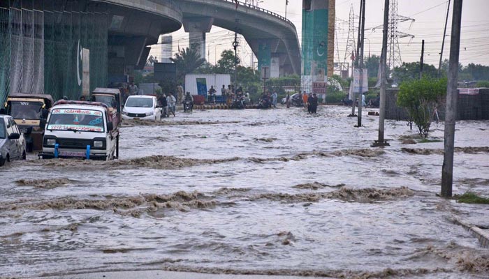 Commuters passing through stagnant rainwater on road after heavy rain in provincial capital. — APP