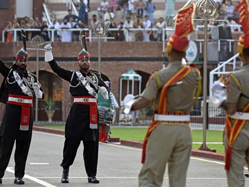 In this photograph taken on August 1, 2022, Indian Border Security Force (BSF) soldiers (in brown) and Pakistani Rangers take part in the Beating the Retreat ceremony at the India-Pakistan Wagah border post, about 35 km from Amritsar. — AFP