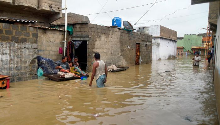 Residents sit on a cart outside their house submerge in flood waters during heavy monsoon rains in Karachi on Tuesday. — AFP