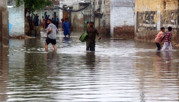 Residents wade through a flooded road after heavy rainfall at Main Qasimabad road.— ONLINE