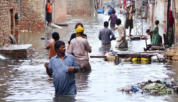 People seen in an inundated street of Jinnah Colony, Latifabad in Hyderabad on August 20, 2022. APP