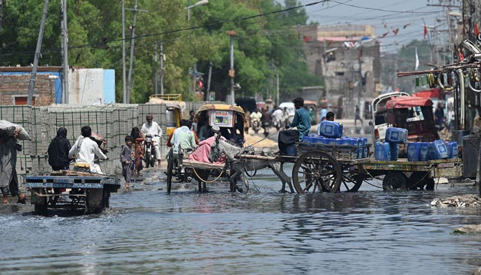 People make their way through the flooded street after heavy monsoon rains in Jacobabad, Sindh province, on September 6, 2022. — AFP