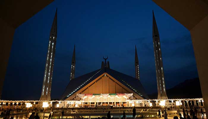 Muslim worshippers arrive for prayers at the illuminated Grand Faisal Mosque on the Lailat al-Qader, also known as the Night of Power, the 27th night of the holy fasting month of Ramadan, in Islamabad on April 28, 2022. — AFP