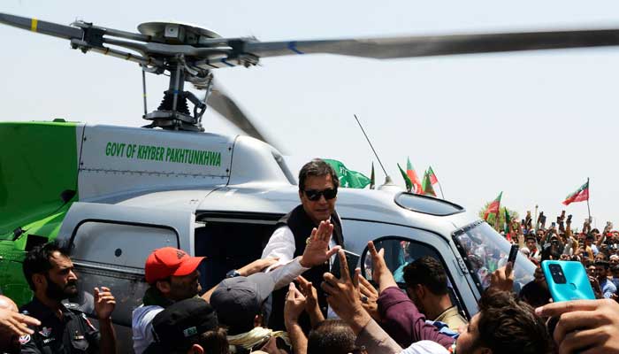 PTI Chairman Imran Khan waves at supporters upon arriving on a helicopter to lead a protest rally in Swabai on May 25, 2022. — AFP