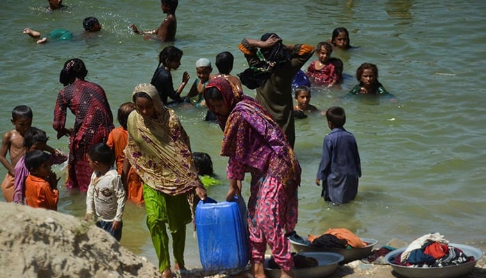 People, displaced because of the floods, carry a canister filled with flood water while taking refuge in a camp, following rains and floods during the monsoon season in Sehwan,in September 20, 2022. — Reuters