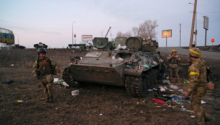 Ukrainian servicemen are seen next to a destroyed armoured vehicle, which they said belongs to the Russian army, outside Kharkiv, Ukraine February 24, 2022. — Reuters